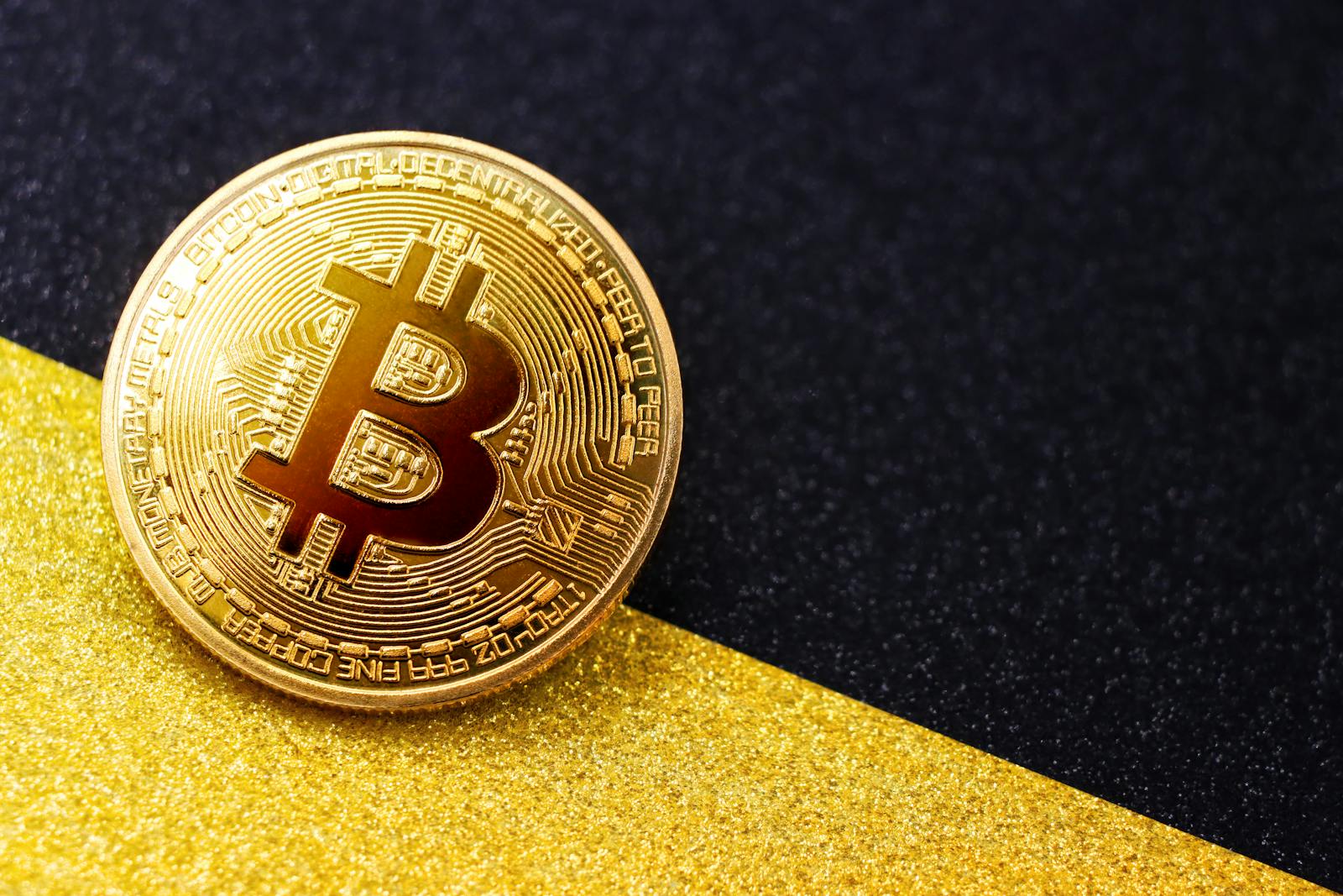 Close-up of a golden Bitcoin on a contrasting black and gold background, symbolizing digital currency and finance.