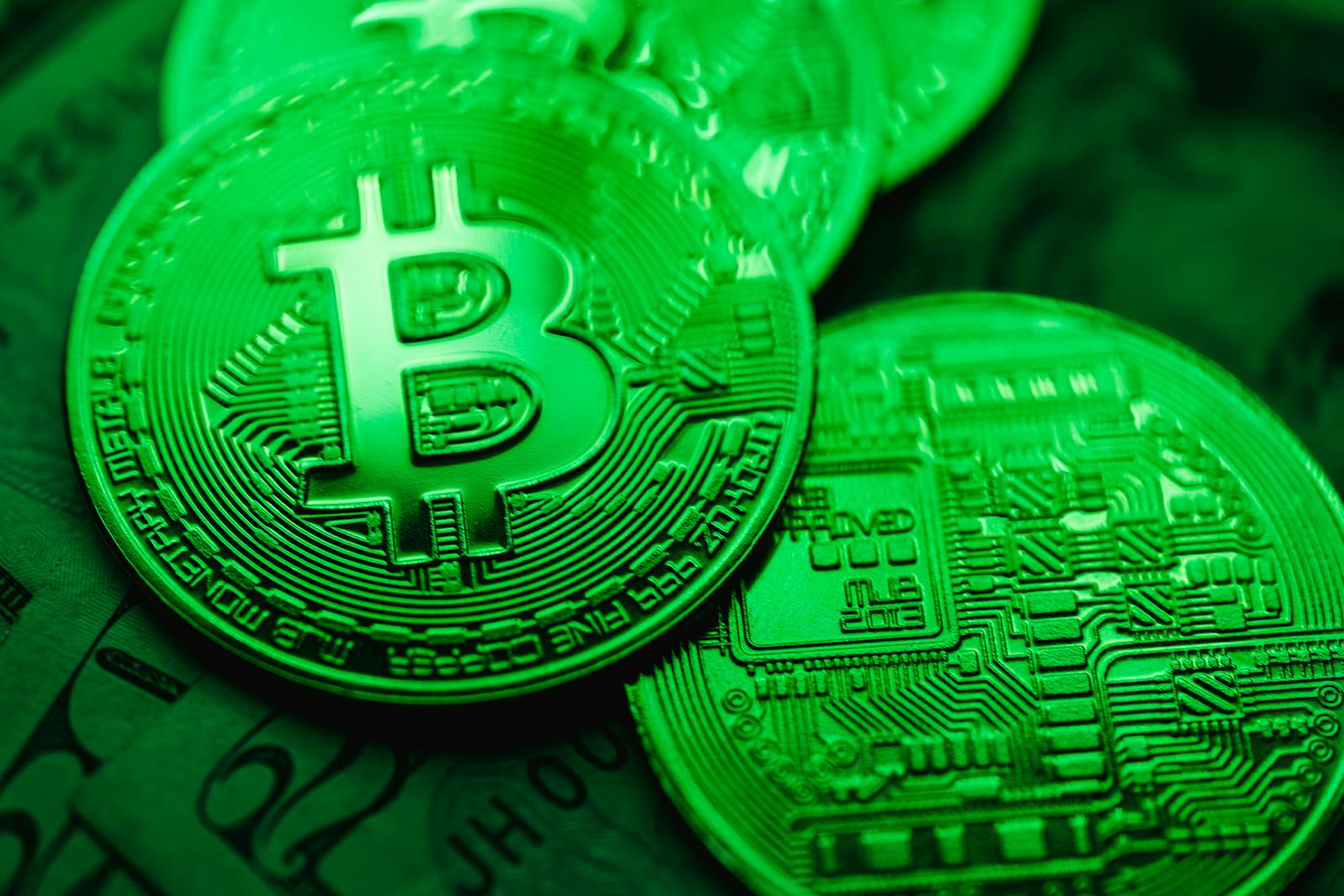 Close-up of green-illuminated Bitcoin coins representing digital currency and blockchain technology.