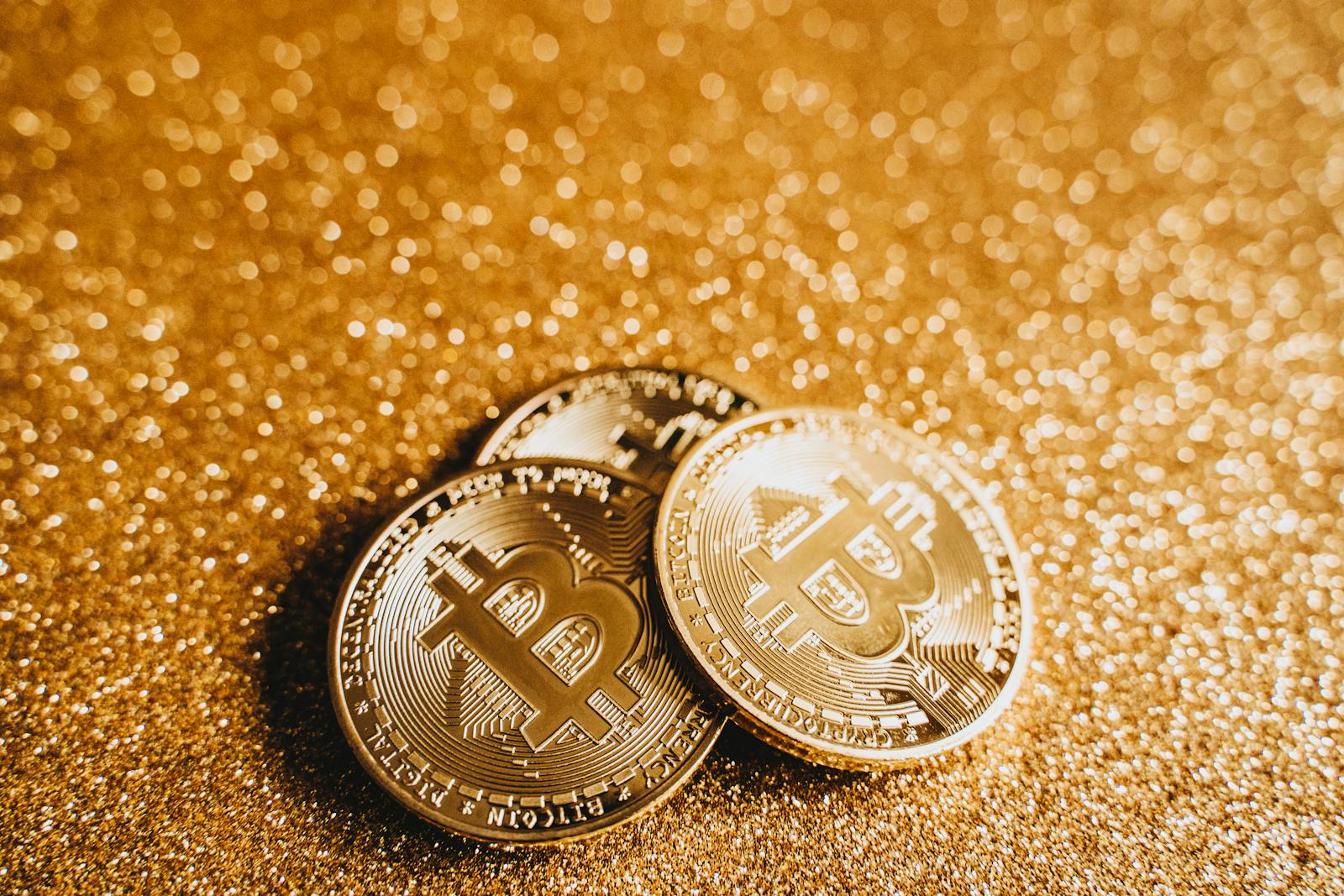 Close-up of gold Bitcoin coins on a glittery surface, symbolizing digital finance and cryptocurrency investment.