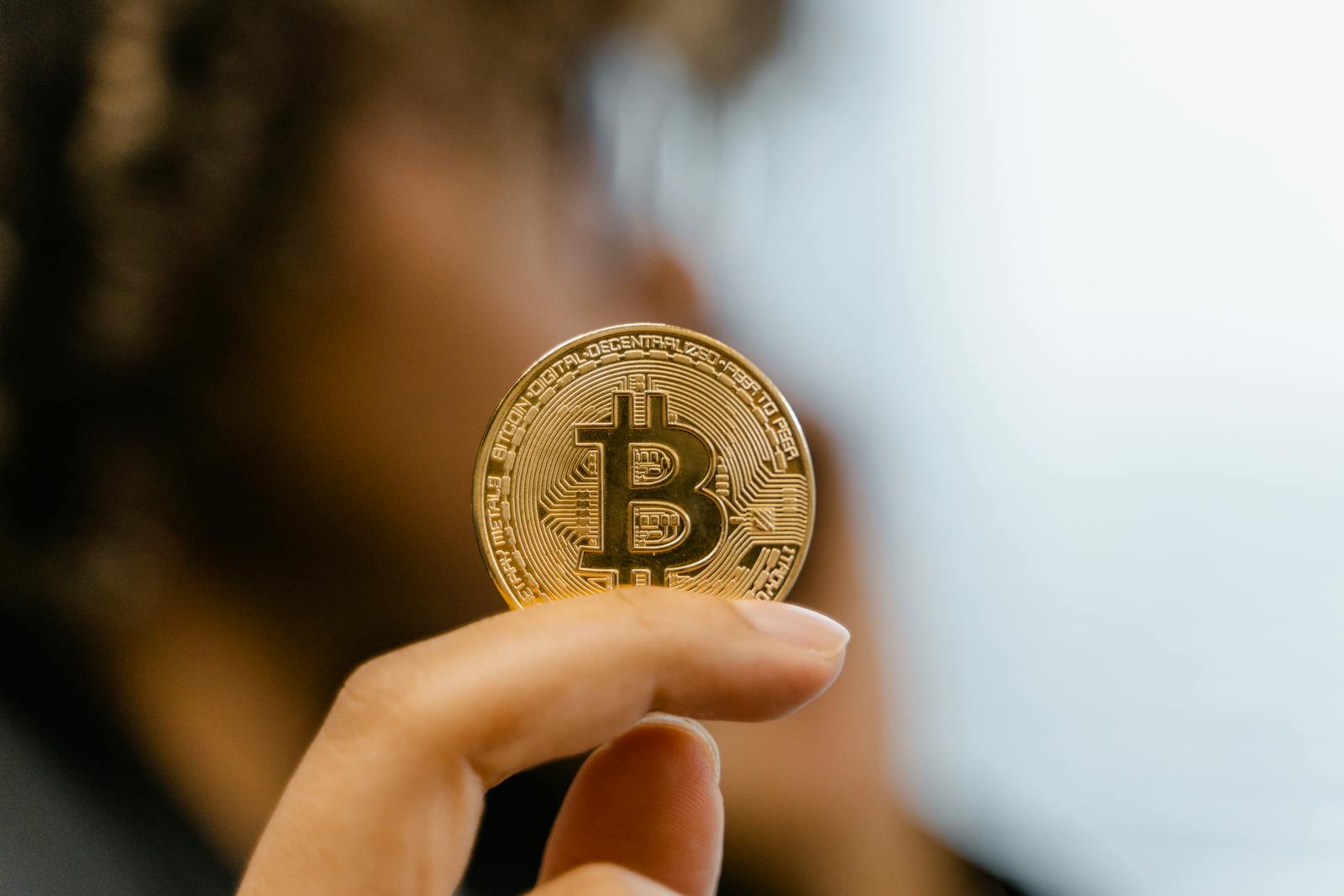 A hand holding a Bitcoin coin, representing cryptocurrency and blockchain technology investment.