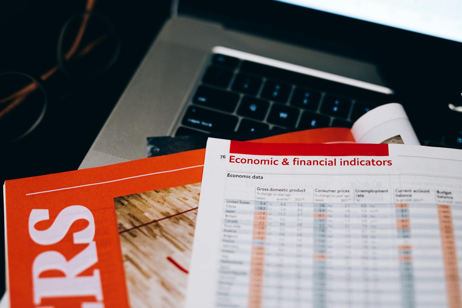 Detailed close-up of economic and financial documents on a laptop keyboard, highlighting data analytics.