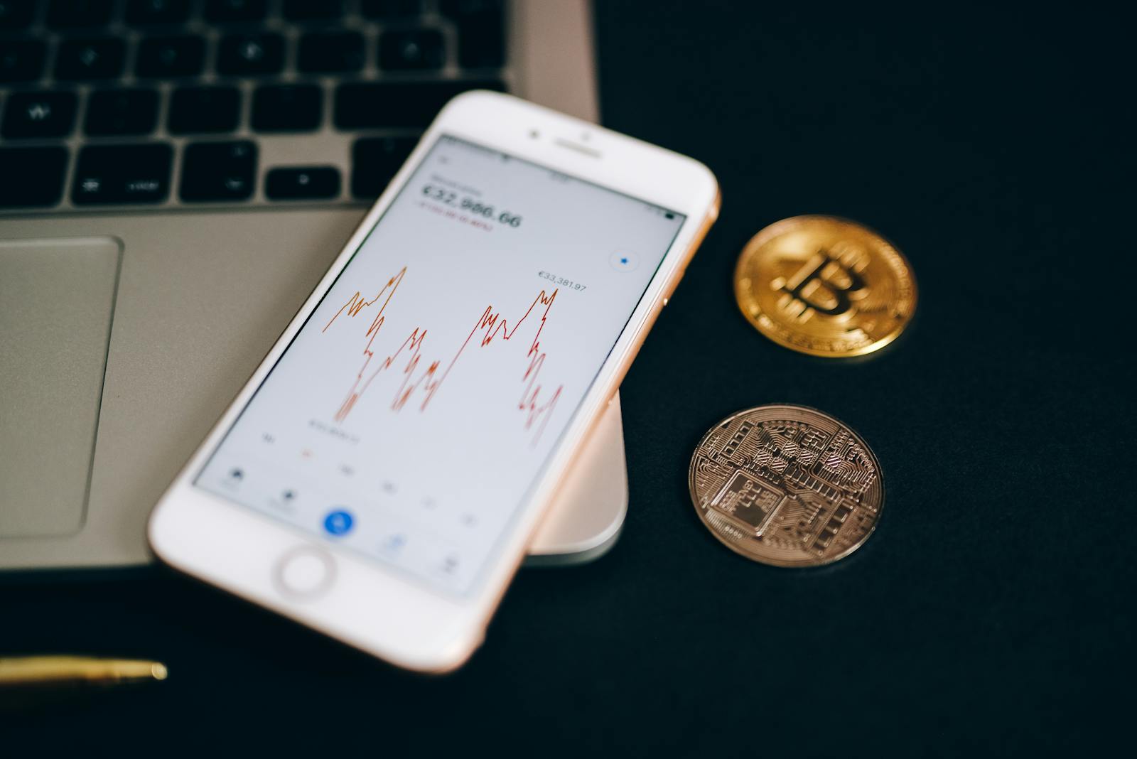 Close-up view of cryptocurrency coins and stock market graph on a smartphone screen.